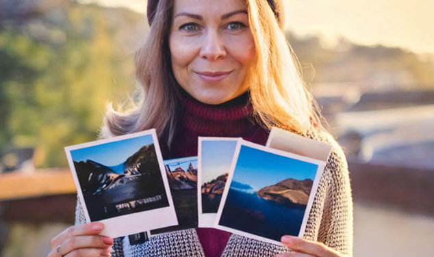 Kvinna håller upp flera polaroidbilder med naturscener på