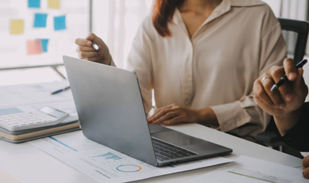 Två personer analyserar data på en laptop